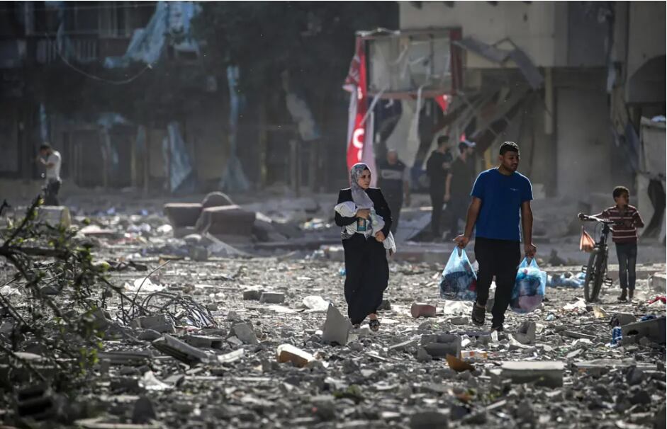 Palestinos caminan entre los escombros tras los ataques aéreos israelíes en el barrio de Tel al-Hawa, en la ciudad de Gaza